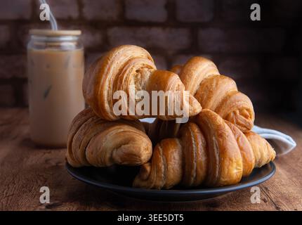 Pastry shop or bakery, puff pastry covered with dark chocolate, on a white plate, with cold coffee or frappe in the background Stock Photo