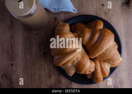 Pastry shop or bakery, puff pastry covered with dark chocolate, on a white plate, with cold coffee or frappe in the background Stock Photo