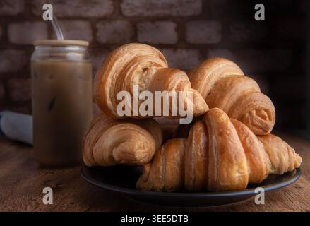 Pastry shop or bakery, puff pastry covered with dark chocolate, on a white plate, with cold coffee or frappe in the background Stock Photo