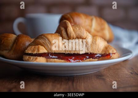 Pastry shop or bakery, puff pastry covered with dark chocolate, on a white plate, with cold coffee or frappe in the background Stock Photo