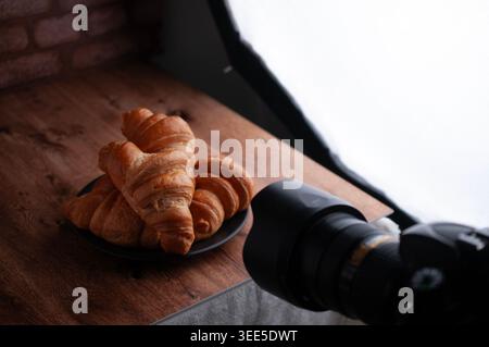 DSLR or Mirrorless photo and video camera, in a pastry session for restaurant and home, with breads or croissants on a plate with artificial light. Stock Photo