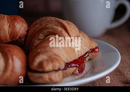 Pastry shop or bakery, puff pastry covered with dark chocolate, on a white plate, with cold coffee or frappe in the background Stock Photo