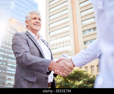 Real estate, happy or men in city with handshake, greeting or deal closed in sale agreement. Business, low angle or realtors in town with hello Stock Photo