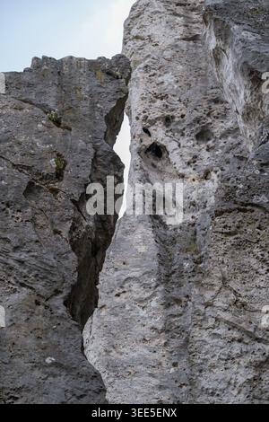 Massive limestone rock formations with deep natural crevice and rugged weathered texture viewed from low angle perspective. Dramatic geological landsc Stock Photo