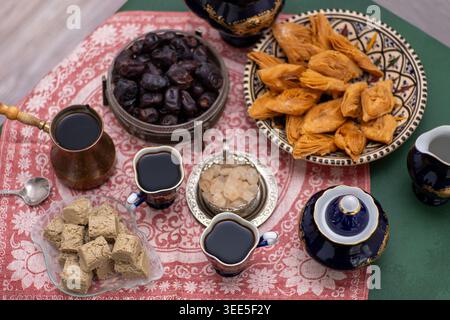 Oriental sweets and coffee on the table. Baklava, halva, Dates fruit for dessert. Food and drink in cezve. Stock Photo