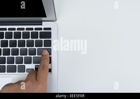 a hand with Index finger touch on  computer keyboard's blank black color key on white background. Stock Photo