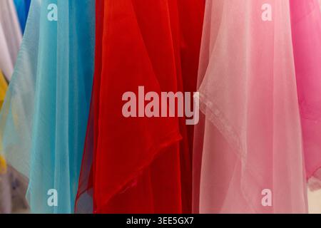 A vibrant and soft close-up view of multiple sheer fabrics draped, showcasing their translucent texture and rich colors Stock Photo