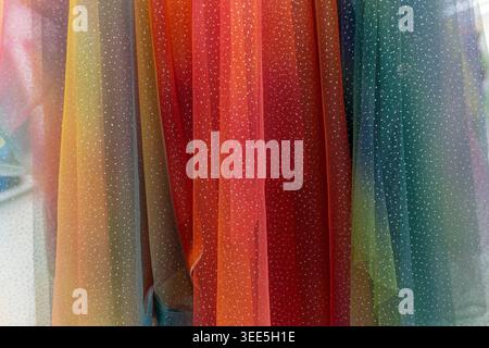 Sparkling sheer fabric draped vertically, showcasing a beautiful rainbow color gradient. Stock Photo