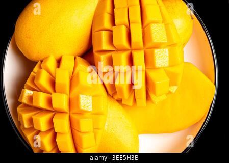 A close up arrangement of ripe yellow mango fruit sliced into cubes on a white plate. Stock Photo