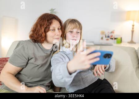 Mother and daughter using smartphone together on couch Stock Photo
