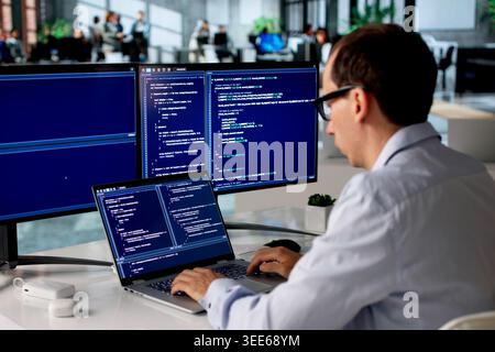 Man In Office Focused On Coding New Web Project Using Laptop Computer. Stock Photo