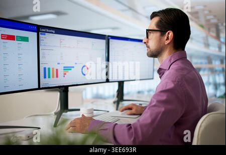 Man Analyzes Lead Scoring Dashboard On Computer To Improve Sales Pipeline. Stock Photo