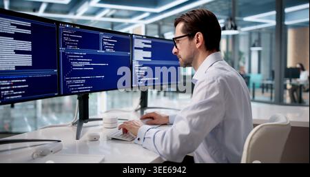 Man Focused On Coding Software At Desk In Quiet Office Space. Stock Photo