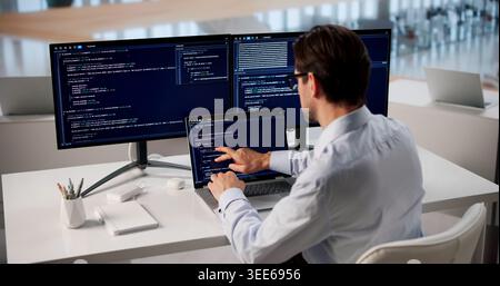 Focused Man Typing Code On Laptop At Modern Office Workspace. Stock Photo