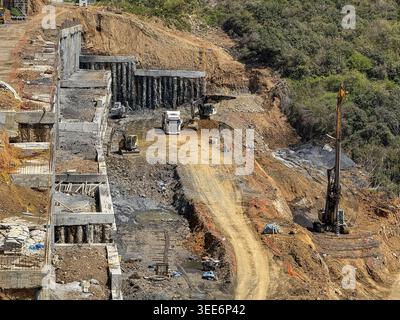 View of a large construction site with excavators, trucks, and a drilling rig working on a hillside with concrete retaining walls Sariyer, Istanbul, T Stock Photo