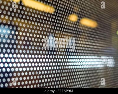 Close up view of perforated window film showing mysterious abstract pattern of dot matrix hole detail with blurred light shining through creating calm Stock Photo