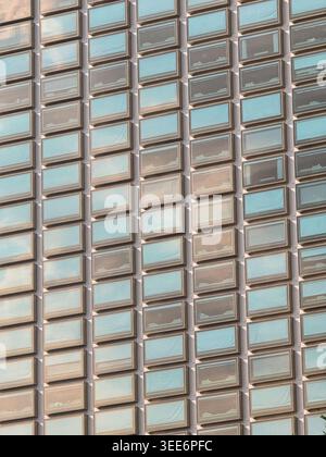 Modern architecture building exterior featuring repeating grid pattern of glass window facade reflecting calm structured skyline creating an imposing Stock Photo