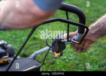 Close-up of Man Pressing Start Button on Lawn Mower Engine Stock Photo