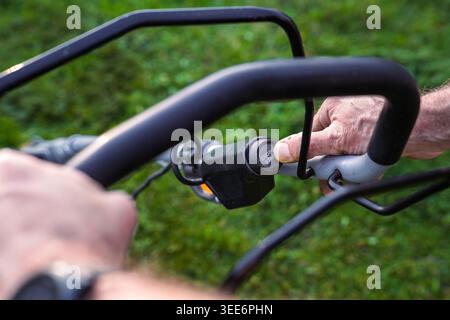 Close-up of Man Pressing Start Button on Lawn Mower Engine Stock Photo