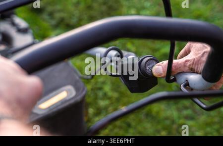 Close-up of Man Pressing Start Button on Lawn Mower Engine Stock Photo
