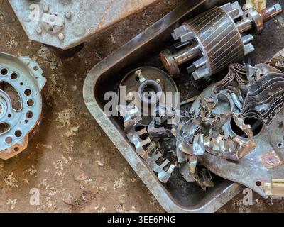 Scrap metal rusty old machine part items show neglected industrial engine iron component. Broken abandoned mechanical pieces sit in dirty tray giving Stock Photo