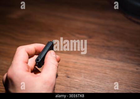 Portable memory stick held in hand over wooden desk with copy space Stock Photo