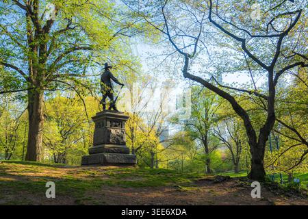 View of The Pilgrim statue surrounded by lush green trees and spring foliage in Central Park New York, New York, United States. Stock Photo