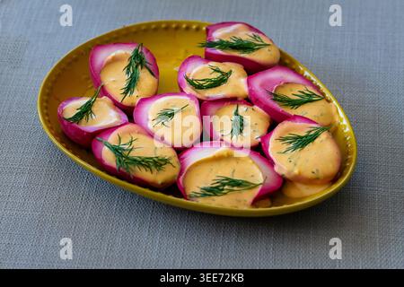 Delicious pink pickled eggs with creamy mustard sauce and fresh dill. A vibrant, gourmet appetizer perfect for catering Stock Photo