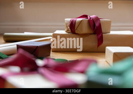 Stack of two kraft wrapped gifts sitting on light wood tabletop with burgundy ribbon Stock Photo