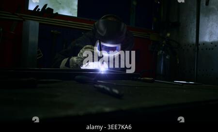 Skilled male welder welding metal bars in a small metalworking production enterprise workshop. Stock Photo
