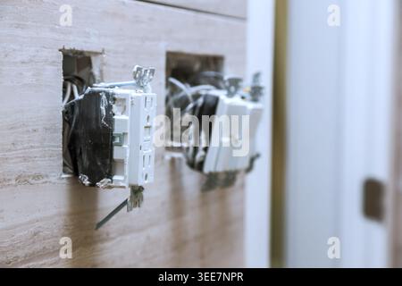 Two electrical outlets are open with wires exposed in home, showing ongoing repair work Stock Photo