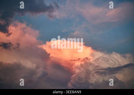 Dramatic sunset clouds glow pink and orange over a deep blue sky, evoking calm and wonder. Stock Photo