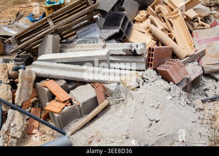 A messy heap of broken concrete, bricks, wood, and other discarded construction materials lies in a disorganized pile Stock Photo