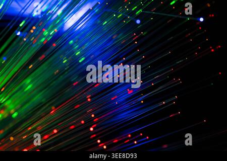 Dynamic abstract image featuring blue, green and red fiber optic light trails with glowing particles on a dark background. Concept of high-speed inter Stock Photo