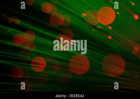 Abstract green fiber optic background with dynamic motion blur and red glowing bokeh circles. Perfect for themes related to digital technology, intern Stock Photo