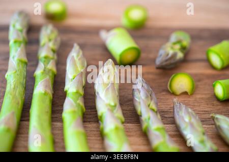 Edible asparagus (Asparagus officinalis) or garden asparagus chopped on a walnut wood chopping board, UK. Concept: cooking, five a day, iron rich food Stock Photo