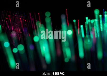 Abstract macro image featuring green and red glowing fiber optic lights with artistic bokeh effects on a dark background. Suitable for digital communi Stock Photo