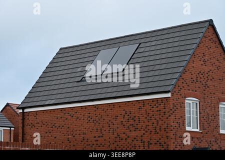 Modern brick house roof with solar panels under overcast sky Stock Photo