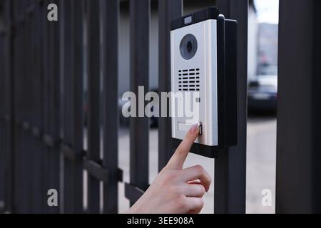 Woman pressing button on intercom panel outdoors, closeup Stock Photo