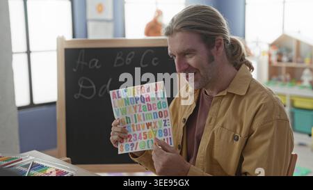 Man teacher holding colorful alphabet card and pointing with pencil at ...