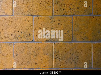 detail closeup of an old stone wall painted yellow orange grunge detail Stock Photo
