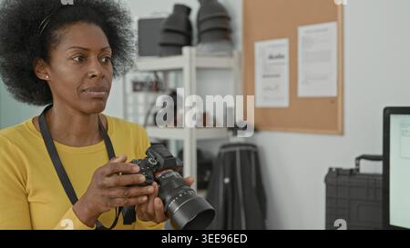 Woman smiling while inspecting a dslr camera, hands on controls and fist pump visible in a green screen studio; creative joy. Stock Photo