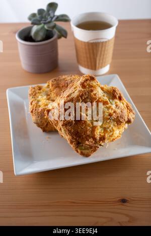 A view of a plate of scones and hot tea in a to-go cup. Stock Photo
