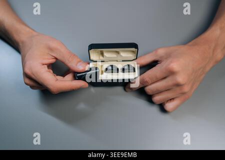 Top view of person checking compact wireless lapel microphone system for smartphones and vlogging, showing transmitter, receiver, charging case and ma Stock Photo