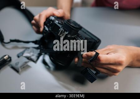 Close-up view of content creator hands setting up and synchronizing wireless lapel microphone system, connecting receiver to digital camera for profes Stock Photo