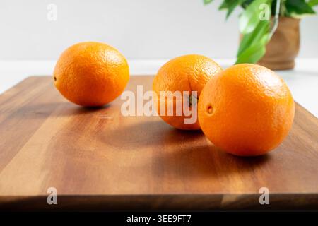 A view of a three navel oranges on a wood board, in a still life setting. Stock Photo