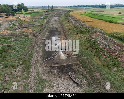 Aerial view of a dried-up riverbed with stranded wooden boats and traditional fishing nets surrounded by agricultural fields in Natore, Rajshahi Divis Stock Photo