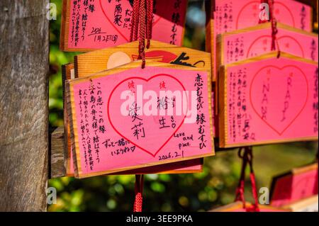 Heart-shaped ema plaques with handwritten wishes hanging at shrine on Enoshima Island, Fujisawa, Japan Stock Photo