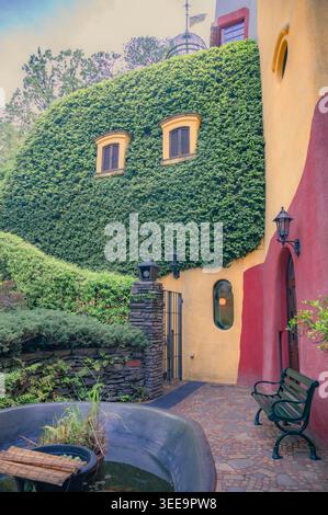 Ivy-covered curved wall with small shuttered windows and garden bench at Ghibli Museum, Mitaka, Tokyo, Japan Stock Photo