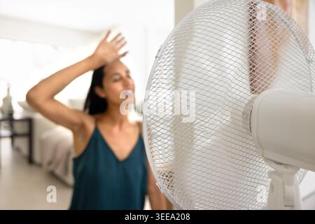 Woman feeling hot and cooling down with fan Stock Photo